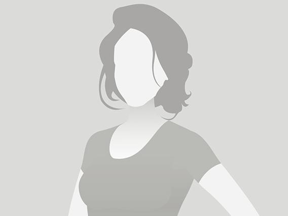 Silhouette einer Frau mit schulterlangen Haaren, die in einem schlichten Oberteil steht, vor grauem Hintergrund.