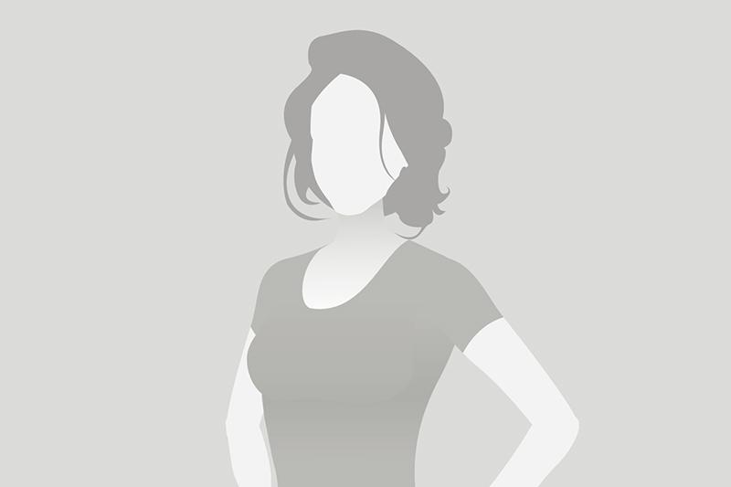 Silhouette einer Frau mit schulterlangen Haaren, die in einem schlichten Oberteil steht, vor grauem Hintergrund.