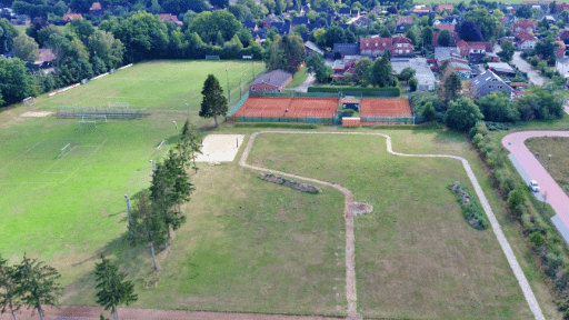 Luftaufnahme eines Sportgeländes mit Fußballplatz, Tennisplätzen und umliegenden Wohngebieten.